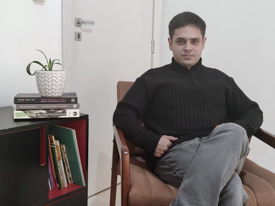 Felipe Rippel sentado na poltrona do consultório, ao lado da estante de livros